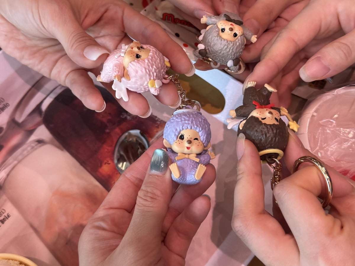Four hands holding pastel Monchhichi keyring figures pulled from Baskin-Robbins play cups